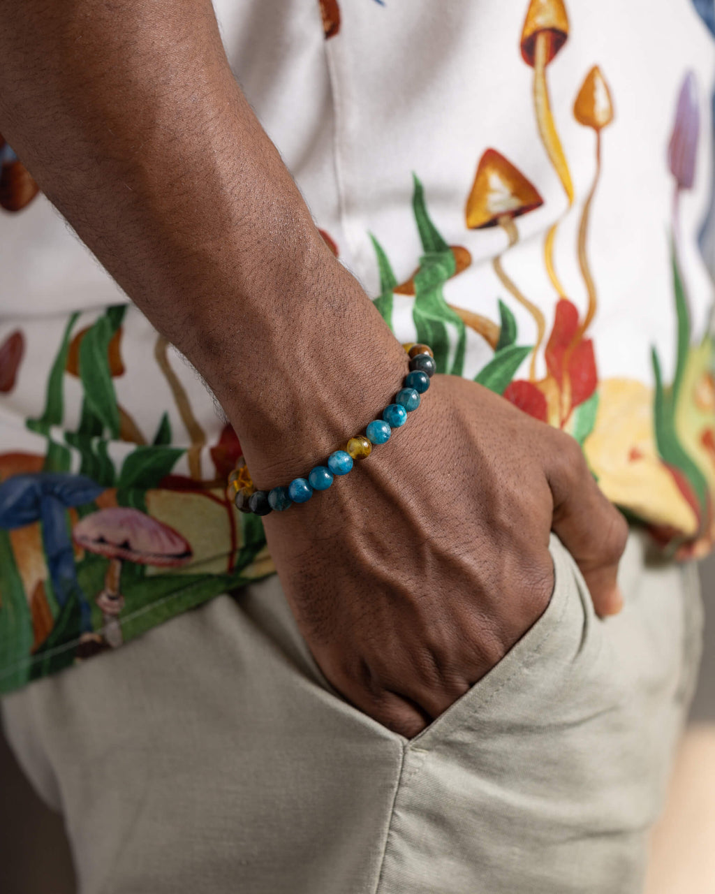 Pulsera Tamanuiterā puesta en la muñeca, mano en el bolsillo de un pantalón claro