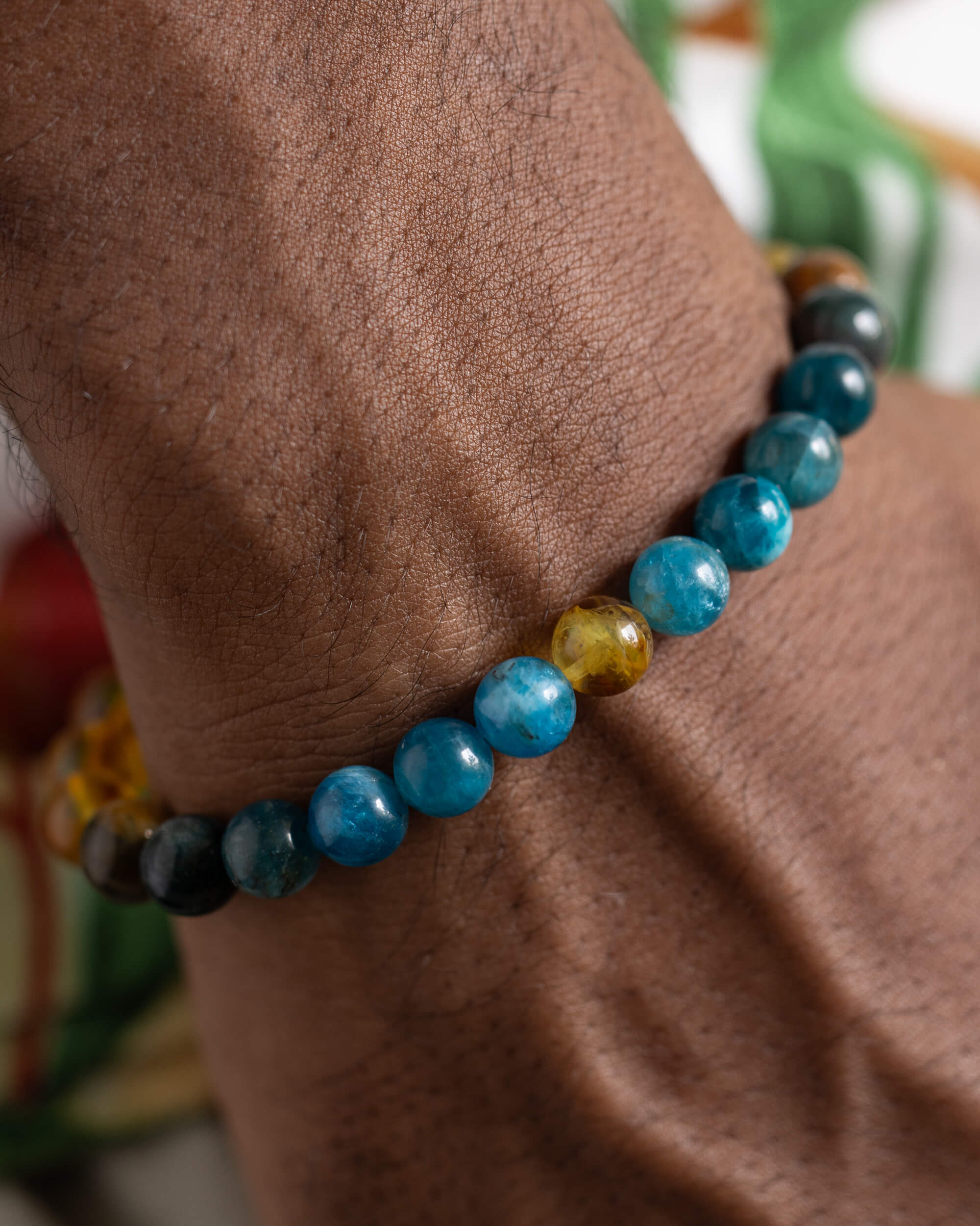 Pulsera Tamanuiterā puesta en la muñeca, cuentas de Apatita Azul y Ámbar visibles