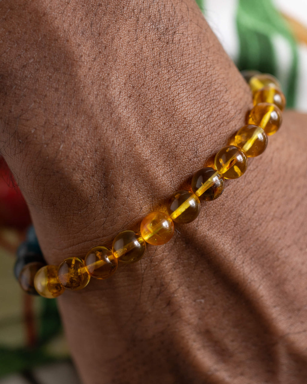 Pulsera Tamanuiterā puesta en la muñeca, cuentas de Ámbar cerca de la mano