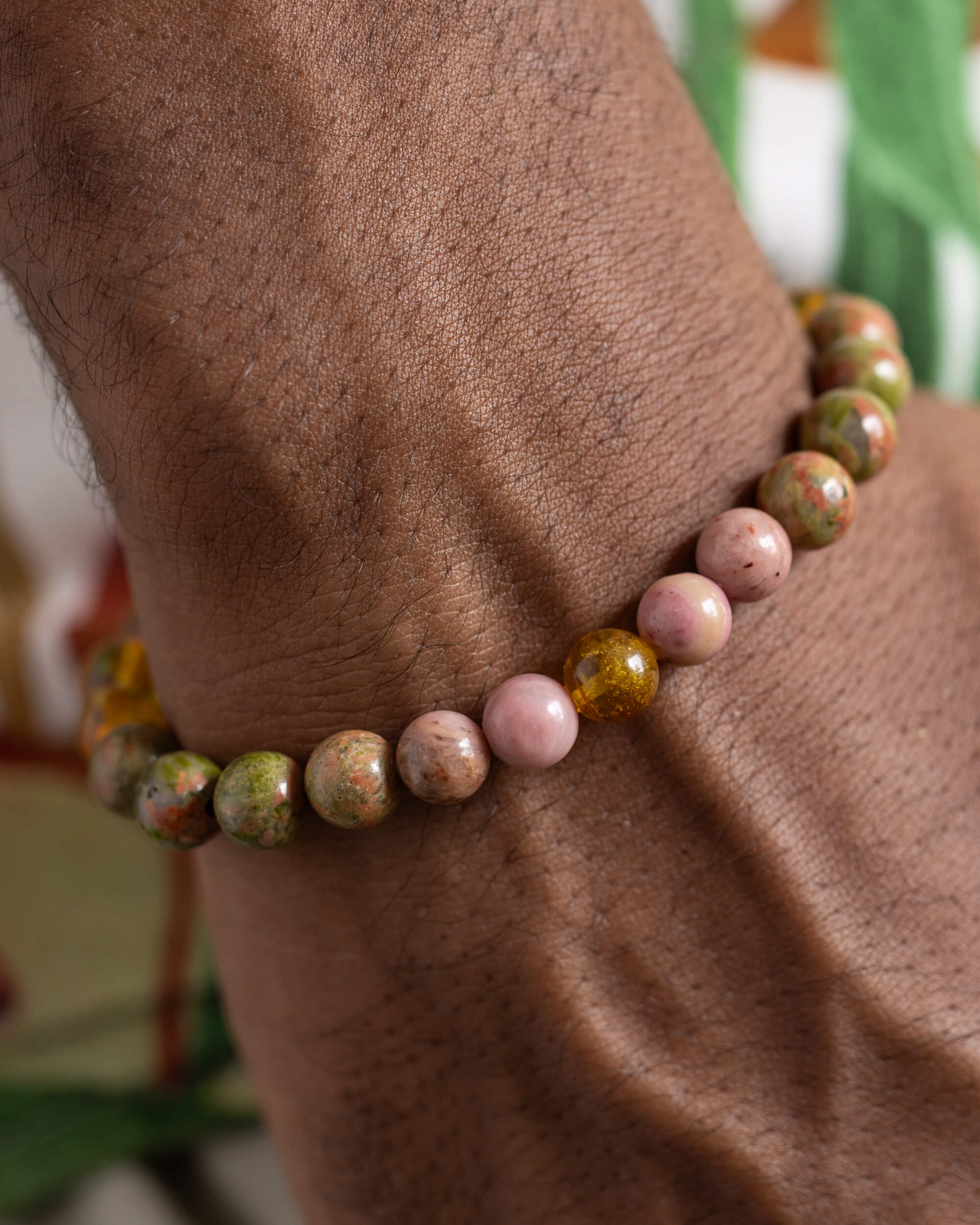Pulsera Dazbog puesta en la muñeca, detalle cercano de Rodonita y Ámbar