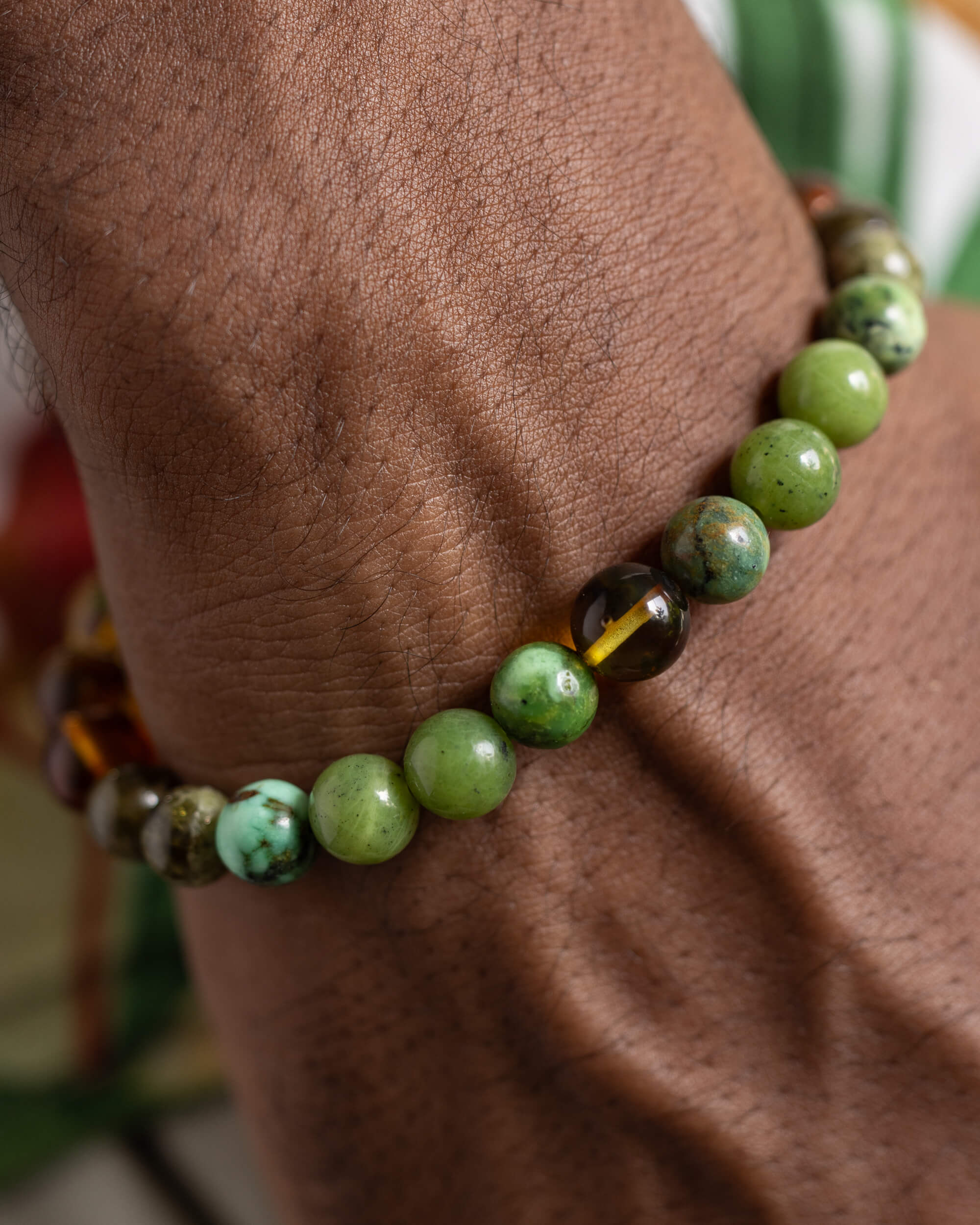 Pulsera Usil puesta en la muñeca, cuentas de Jade Verde y Ámbar visibles