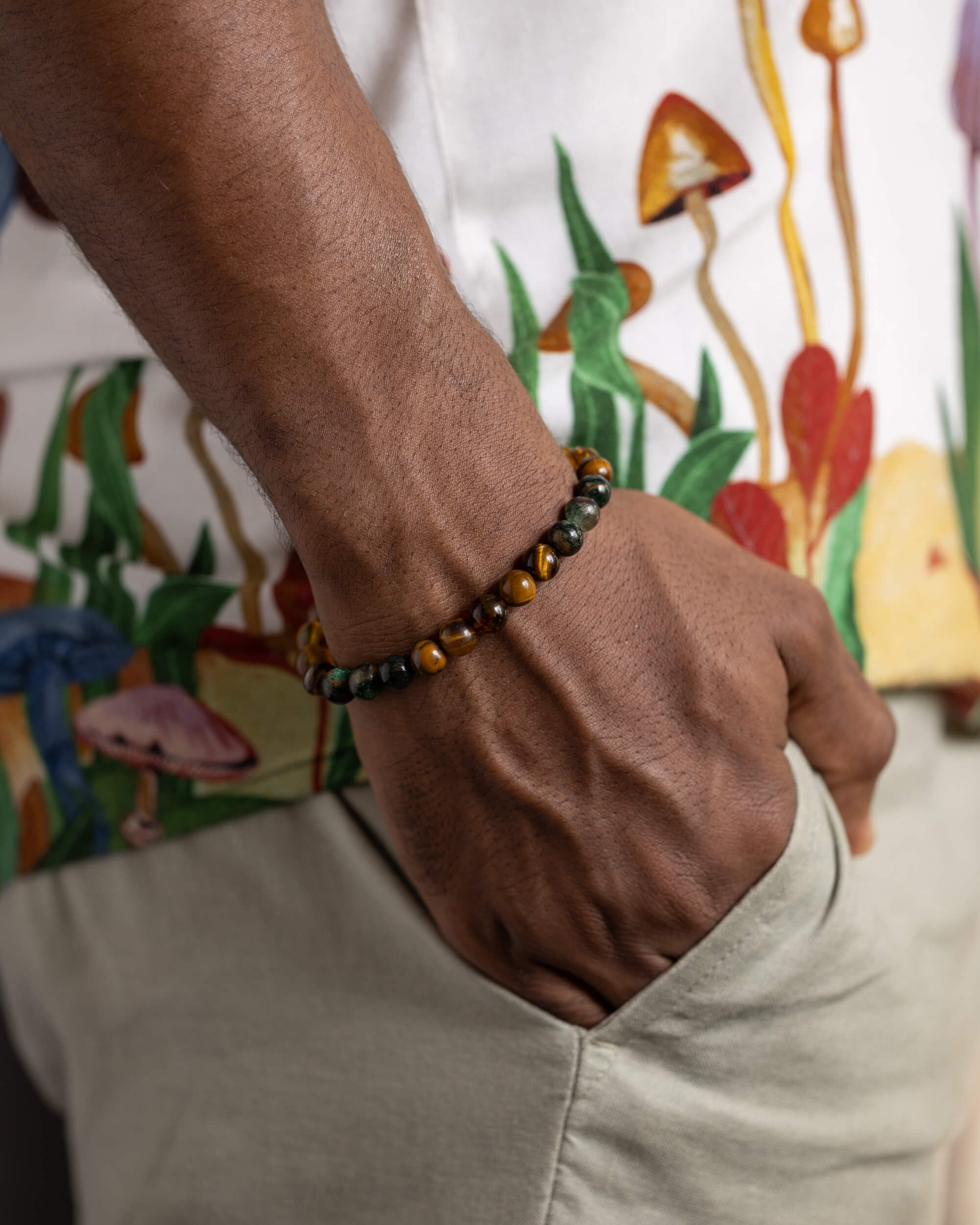 Pulsera Freyr puesta en la muñeca, cuentas de Ojo de Tigre y Ámbar sobre camisa estampada
