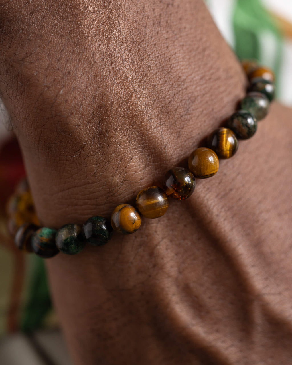 Pulsera Freyr puesta en la muñeca, detalle cercano de Ojo de Tigre y Esmeralda en Matriz de Biotita