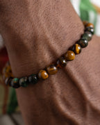 Pulsera Freyr puesta en la muñeca, detalle cercano de Ojo de Tigre y Esmeralda en Matriz de Biotita