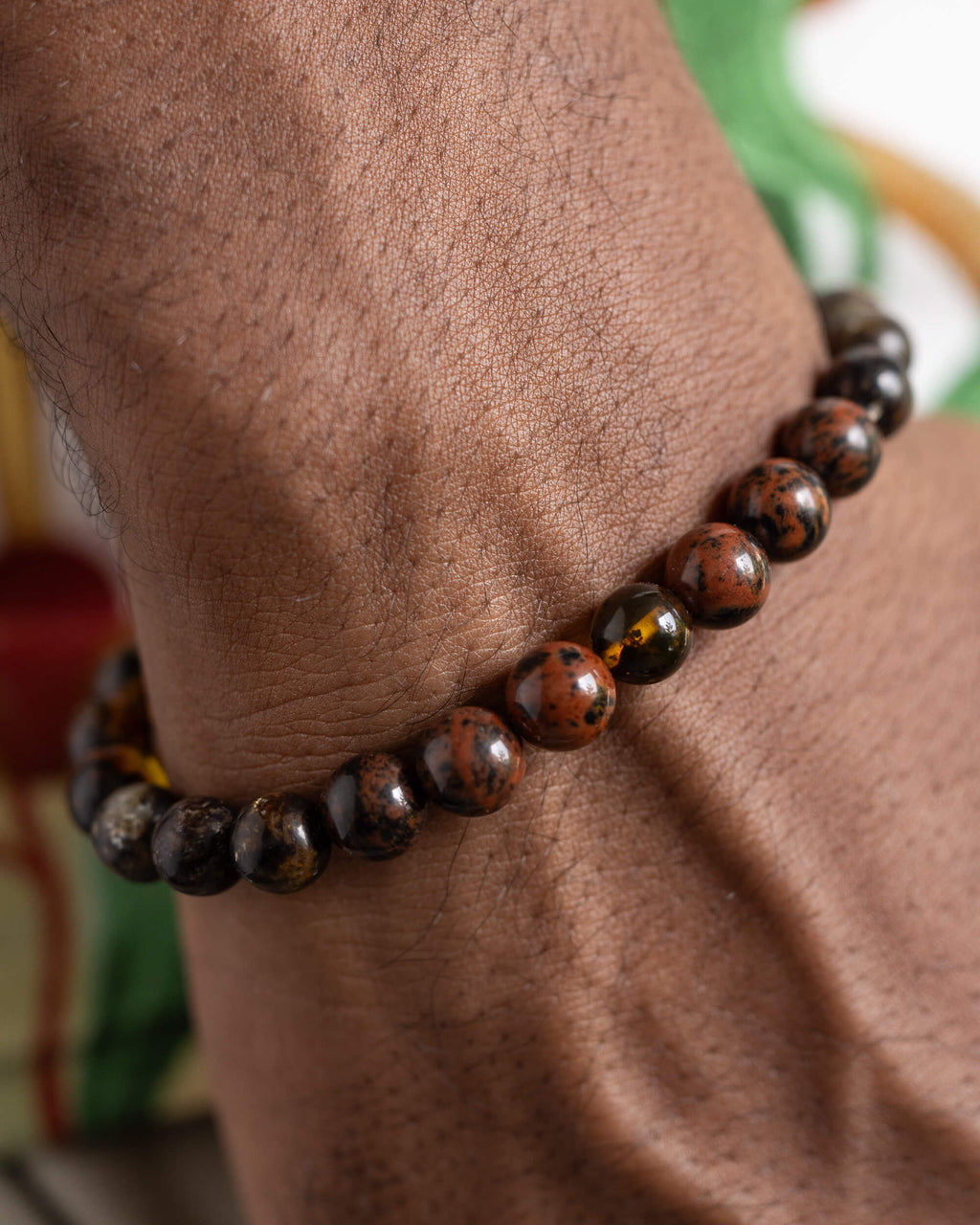 Pulsera Kinich Ahau puesta en la muñeca, tonos rojizos y oscuros visibles