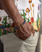 Pulsera Utu puesta en la muñeca, cuentas de Lapislázuli y Ámbar sobre camisa estampada