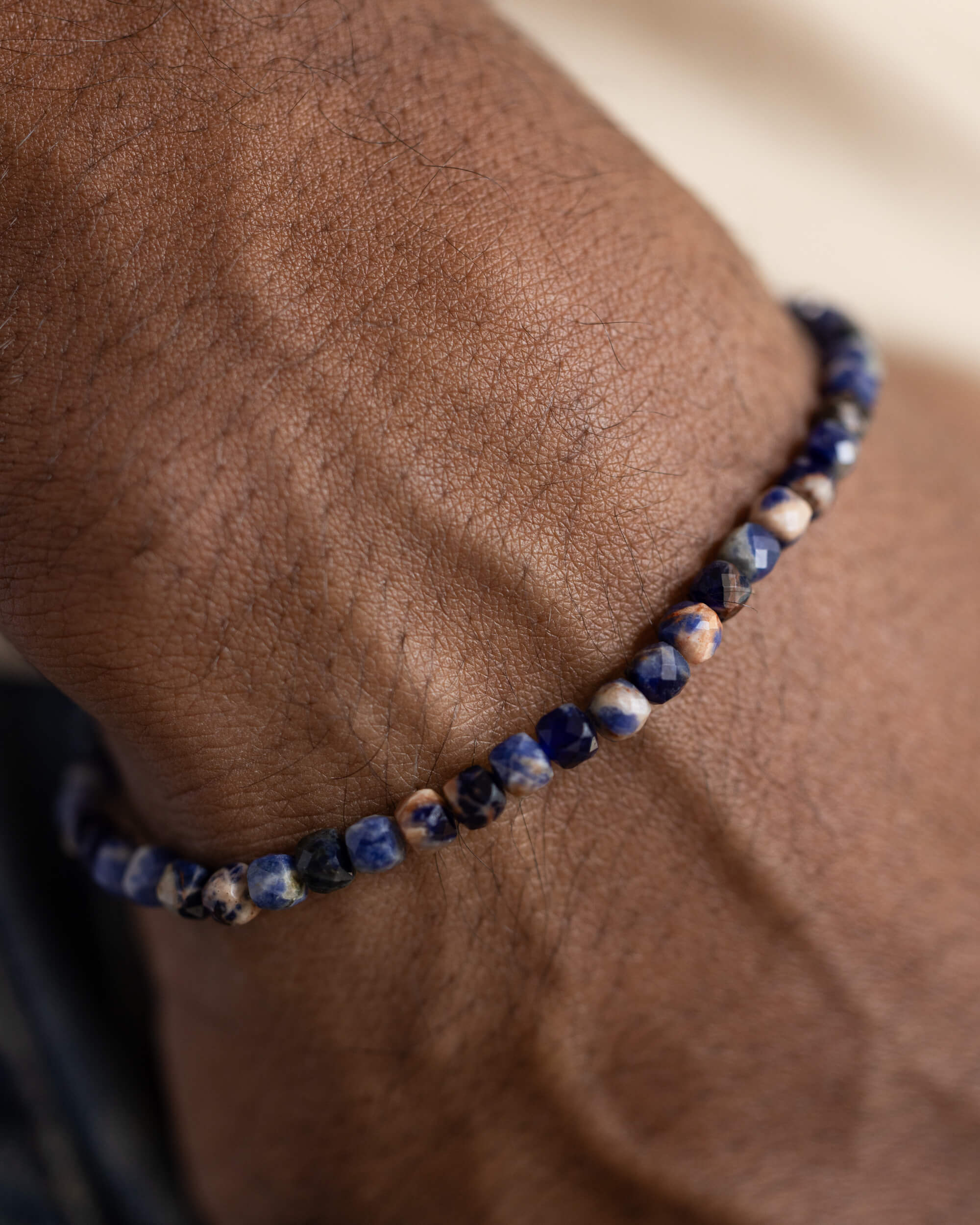 Pulsera de Sodalita puesta en la muñeca, cuentas azules sobre la piel