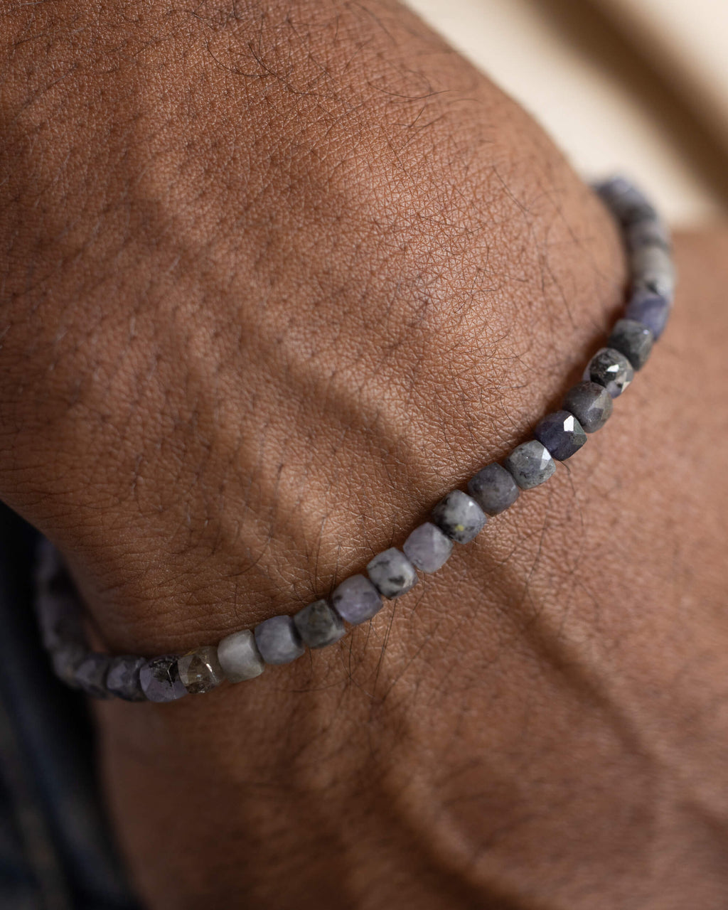 Pulsera de Tanzanita puesta en la muñeca, cuentas facetadas sobre la piel