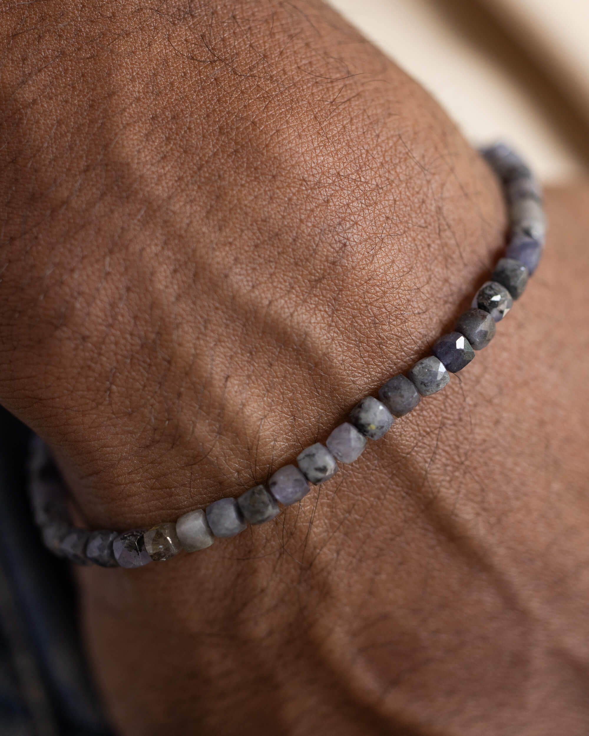 Pulsera de Tanzanita puesta en la muñeca, cuentas facetadas sobre la piel