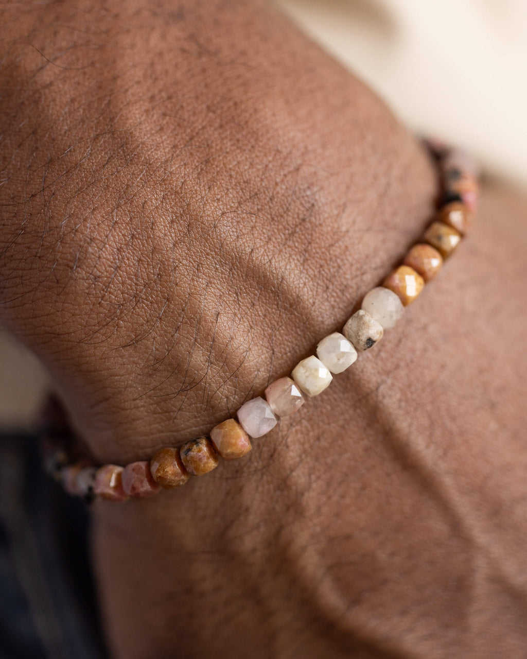 Pulsera de Rodonita puesta en la muñeca, cuentas claras y doradas visibles