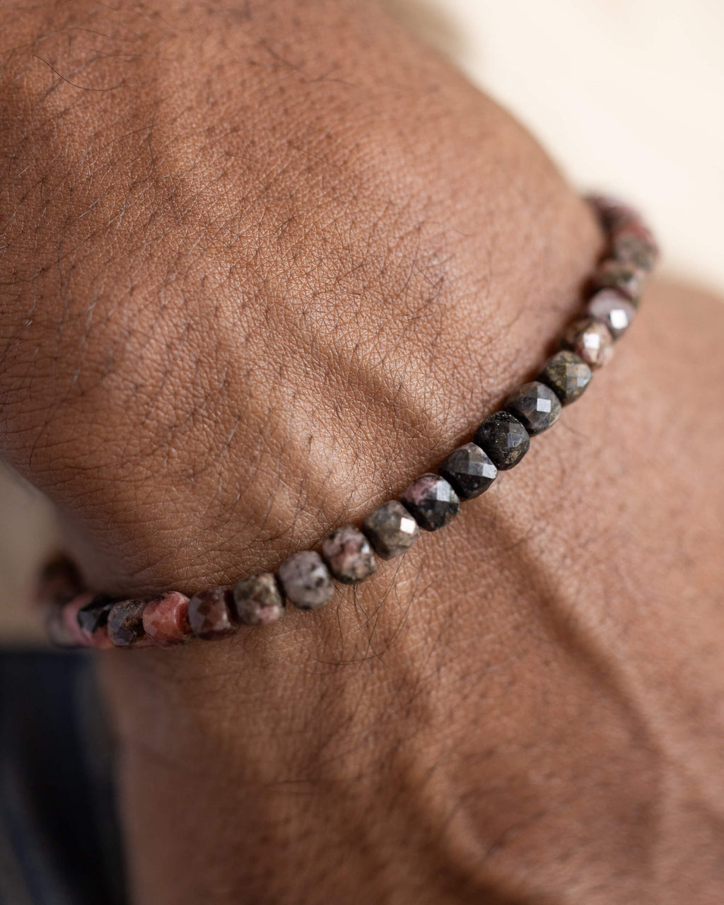 Pulsera de Rodonita Encaje Negro puesta en la muñeca, cuentas oscuras visibles