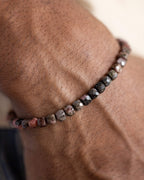 Pulsera de Rodonita Encaje Negro puesta en la muñeca, cuentas oscuras visibles