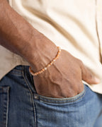 Pulsera de Piedra Sol Naranja puesta en la muñeca, mano en el bolsillo de un jean