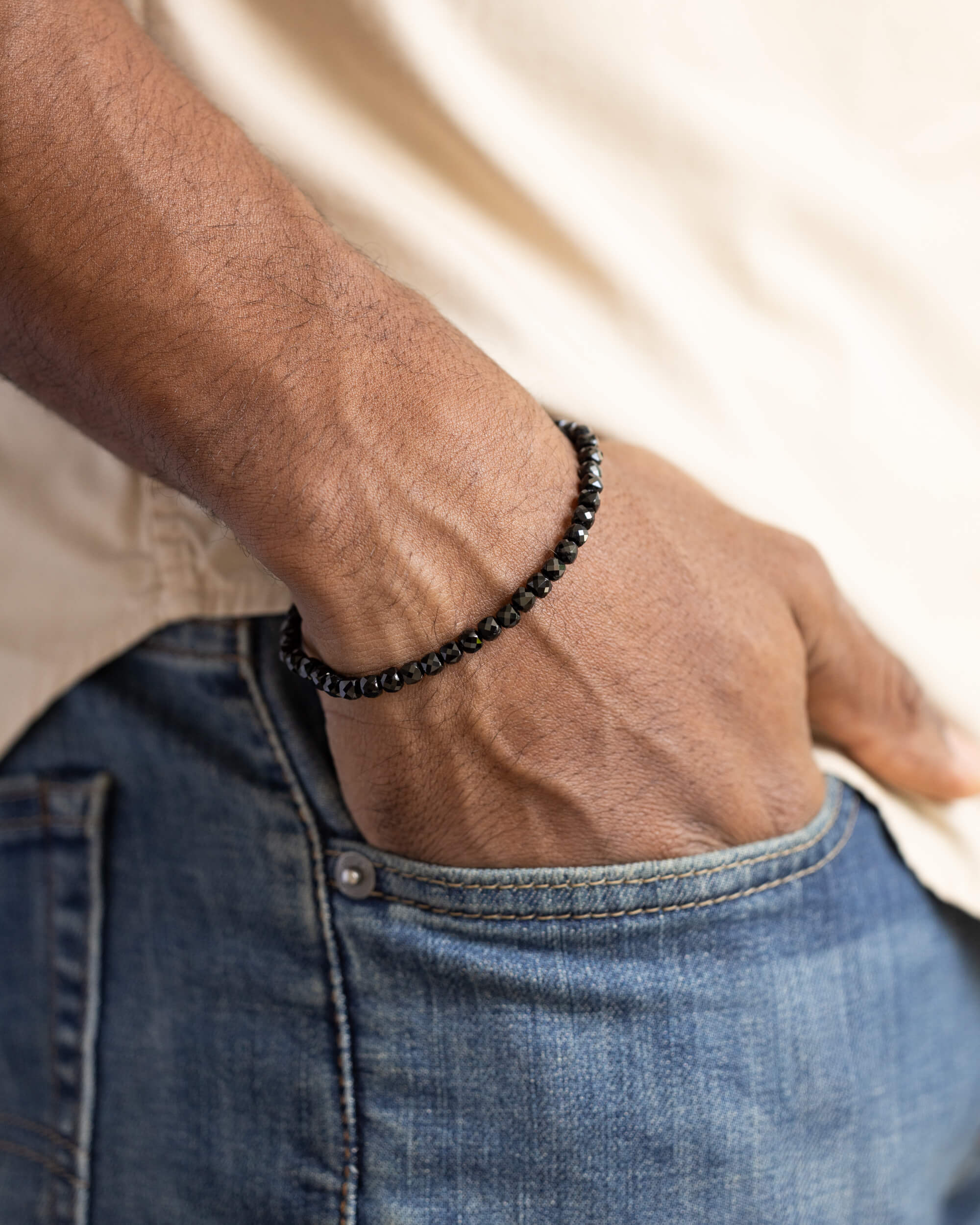 Pulsera de Espinela Negra puesta en la muñeca, con la mano en el bolsillo del pantalón
