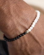 Pulsera Unidad puesta en la muñeca, con las cuentas de Piedra Luna y Turmalina Negra visibles