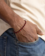 Pulsera de Coral Rojo y Turmalina Negra puesta, mano dentro del bolsillo