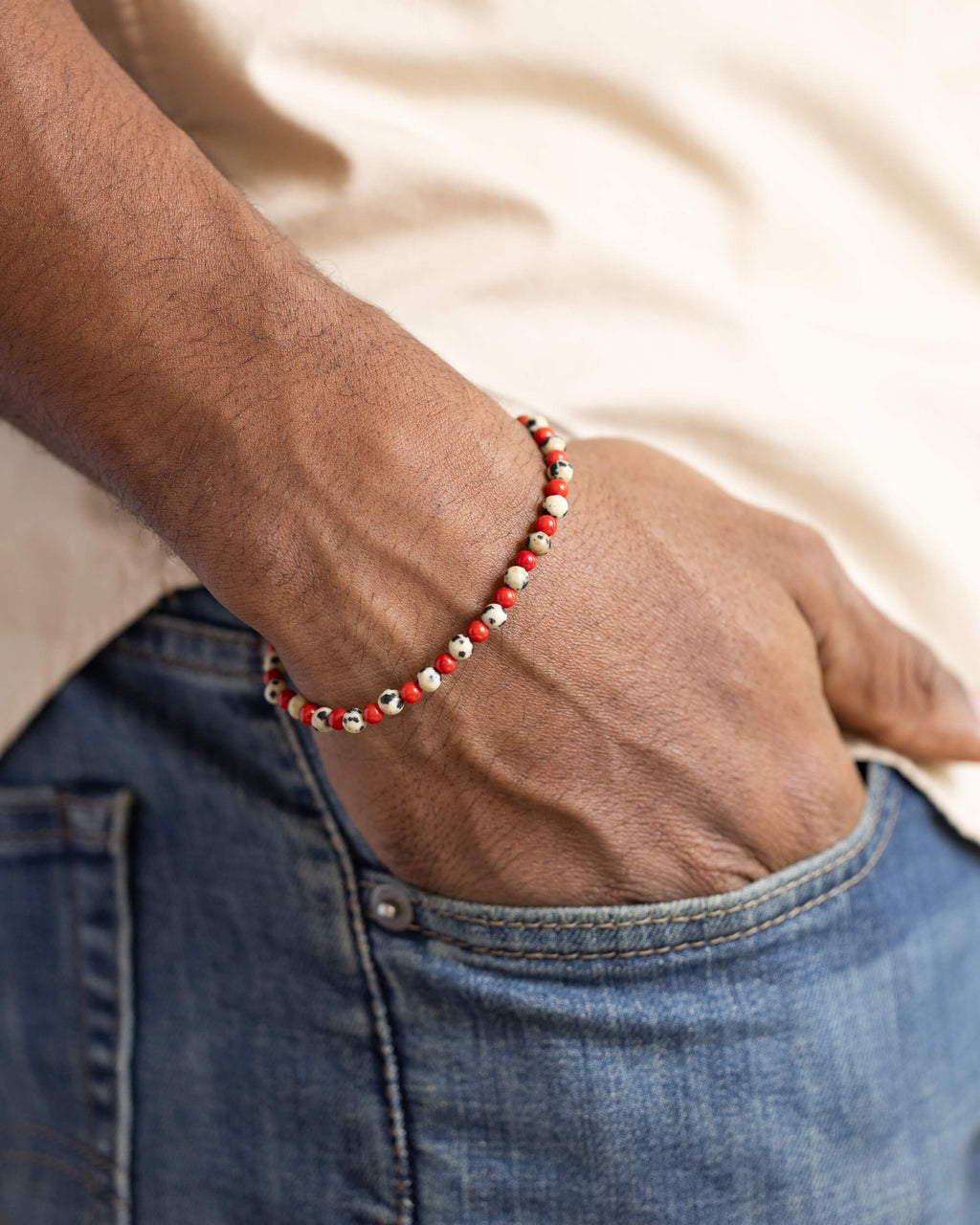 Pulsera de Jaspe Dálmata y Coral Rojo puesta, mano dentro del bolsillo