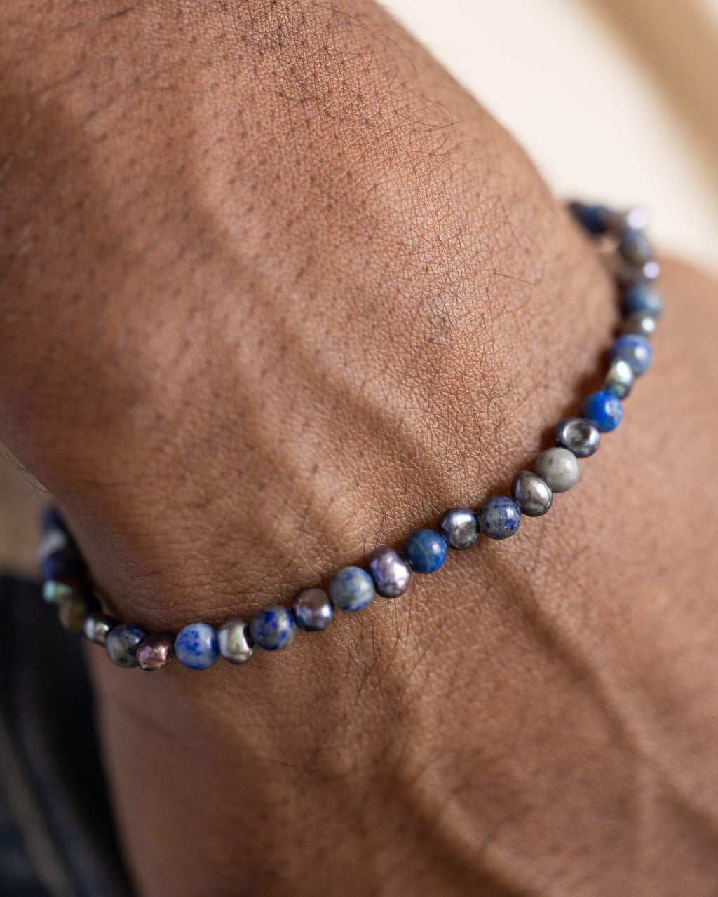 Pulsera de Lapislázuli y Perla Negra puesta en la muñeca, mano en el bolsillo