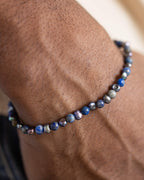 Pulsera de Lapislázuli y Perla Negra puesta en la muñeca, mano en el bolsillo
