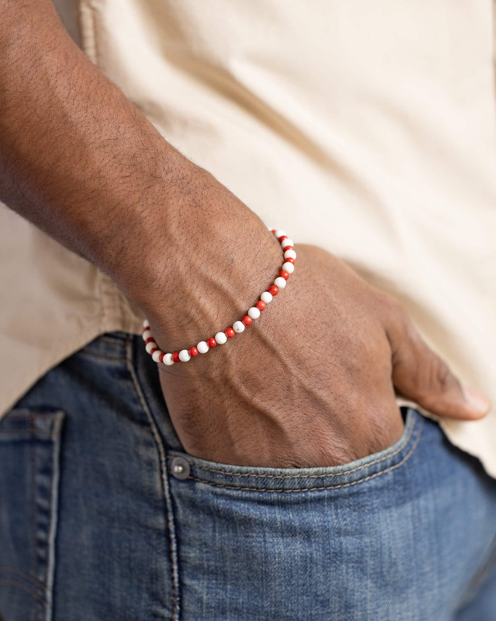 Pulsera de Coral Rojo y Howlita puesta, la mano en el bolsillo