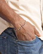 Pulsera de Amatista y Cuarzo Rutilado puesta, la mano en el bolsillo