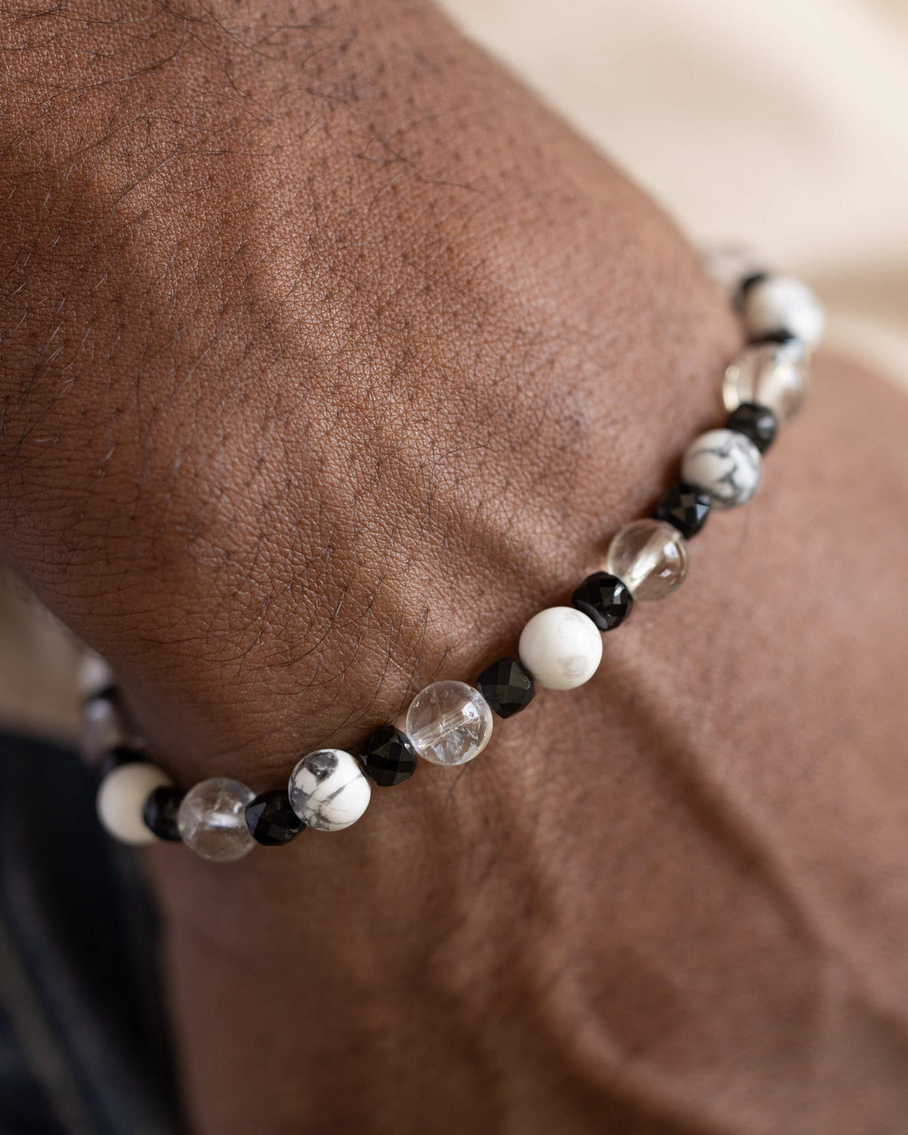 Pulsera de Espinela Negra, Howlita y Cuarzo Transparente puesta, rodeando la muñeca