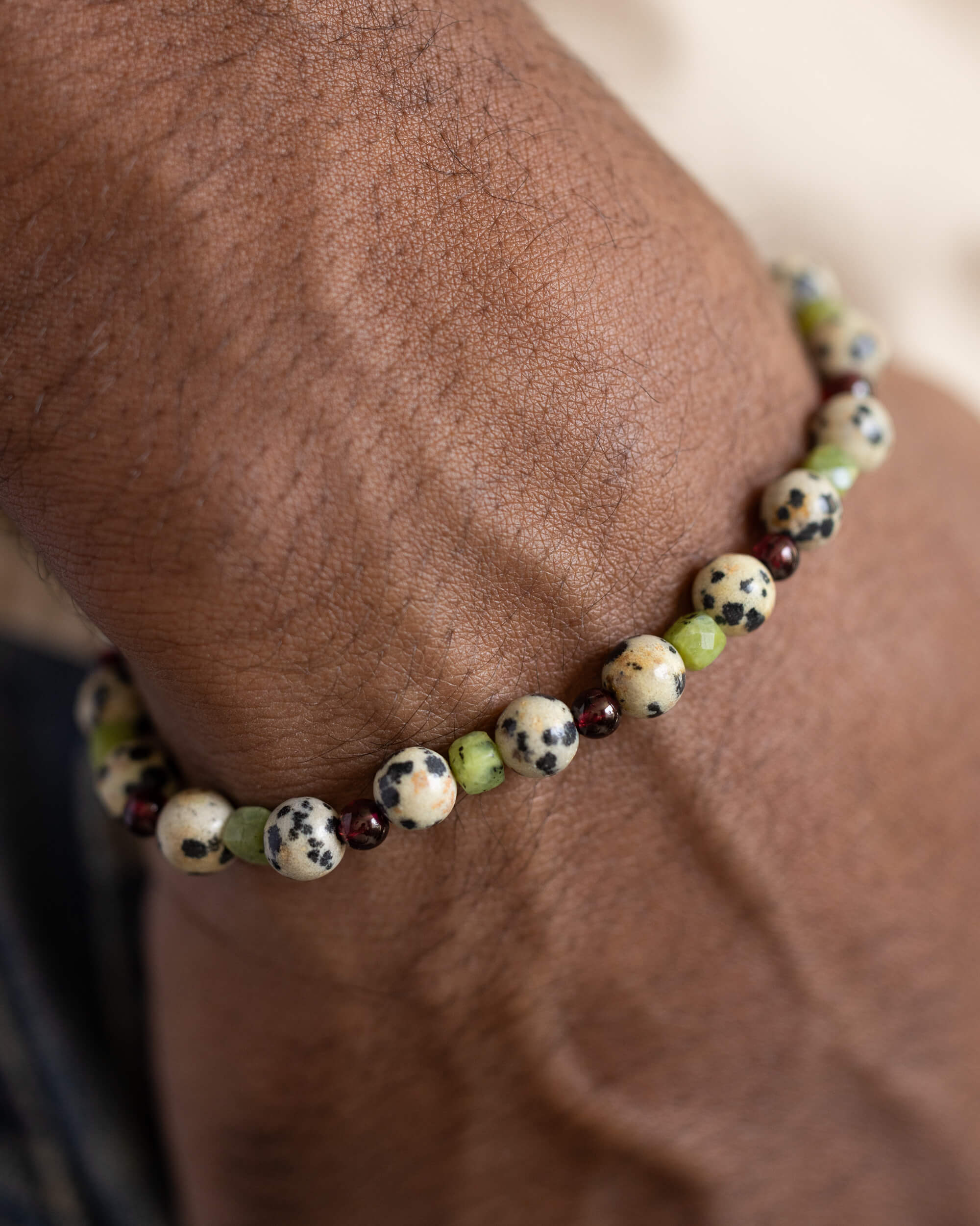 Pulsera Guerrero Alegre puesta en la muñeca, con cuentas de Jaspe Dálmata, Jade Verde y Granate