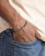 Pulsera de Labradorita, Tanzanita y Ojo de Halcón puesta, mano en el bolsillo