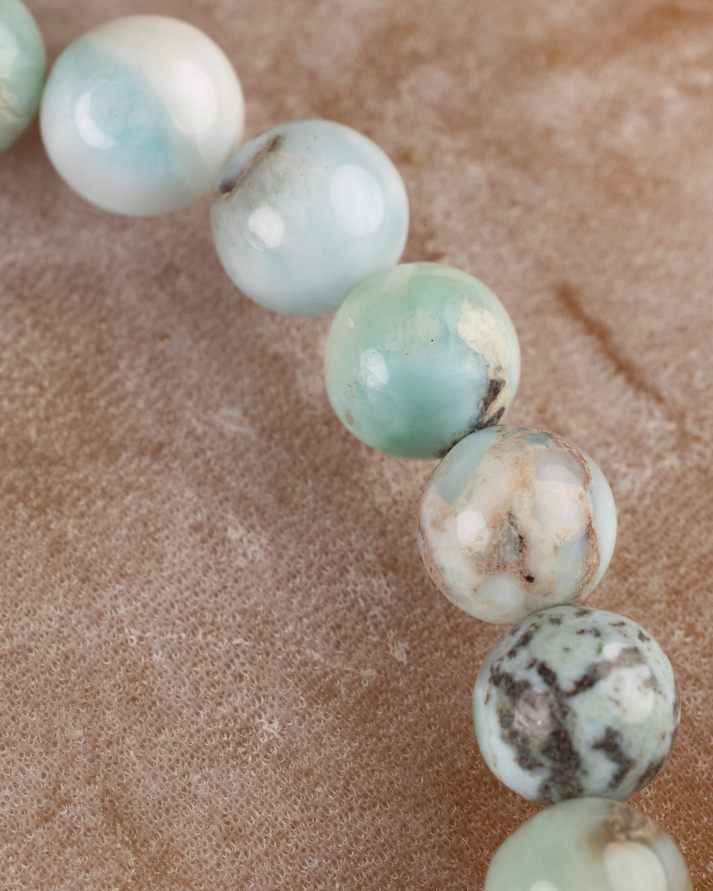 Detalle macro de las cuentas de Larimar con vetas cafes y azules