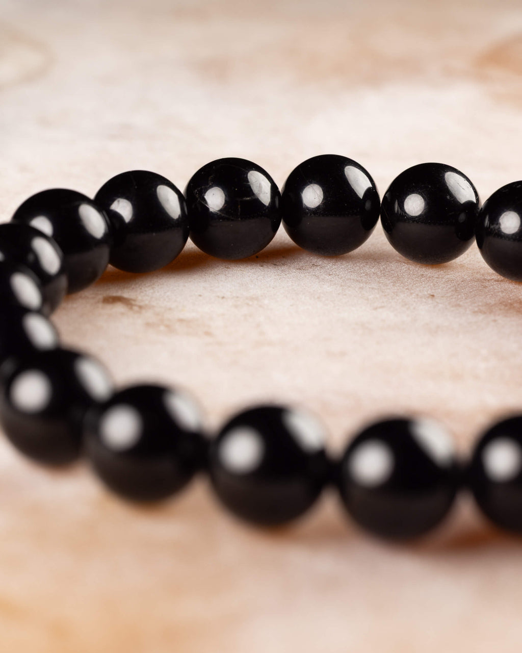 Pulsera de Turmalina Negra en curva, mostrando el brillo uniforme de sus cuentas