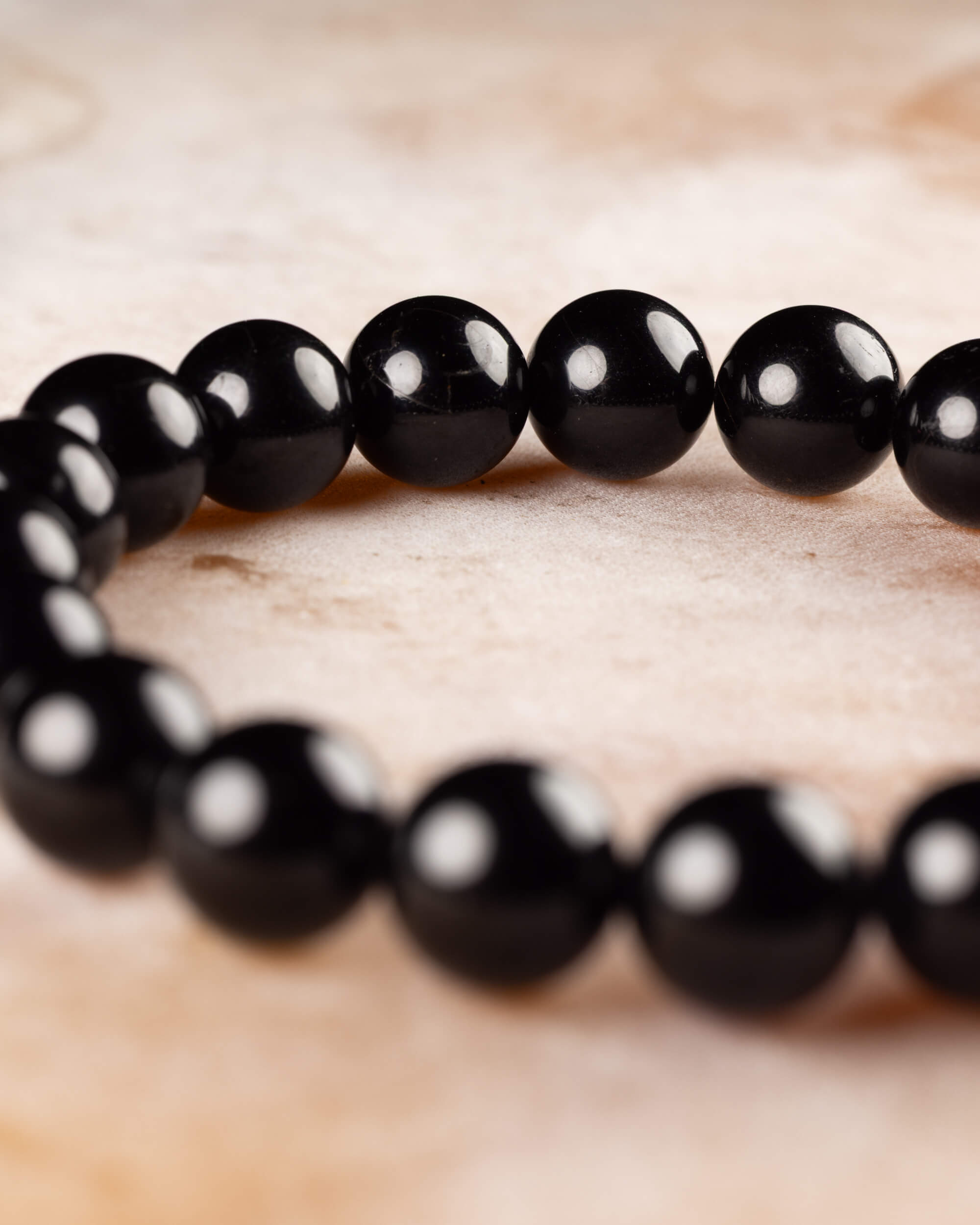Pulsera de Turmalina Negra en curva, mostrando el brillo uniforme de sus cuentas