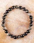 Pulsera de Obsidiana Plateada de 8 mm, pieza completa sobre superficie de mármol claro