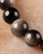 Cuentas de Obsidiana Plateada en primer plano, alternando tono negro y gris metálico