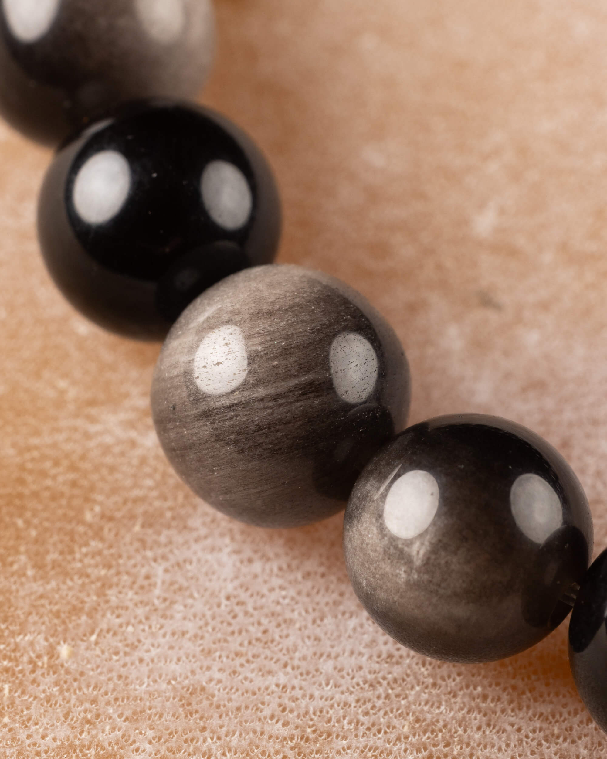 Cuentas de Obsidiana Plateada en primer plano, alternando tono negro y gris metálico
