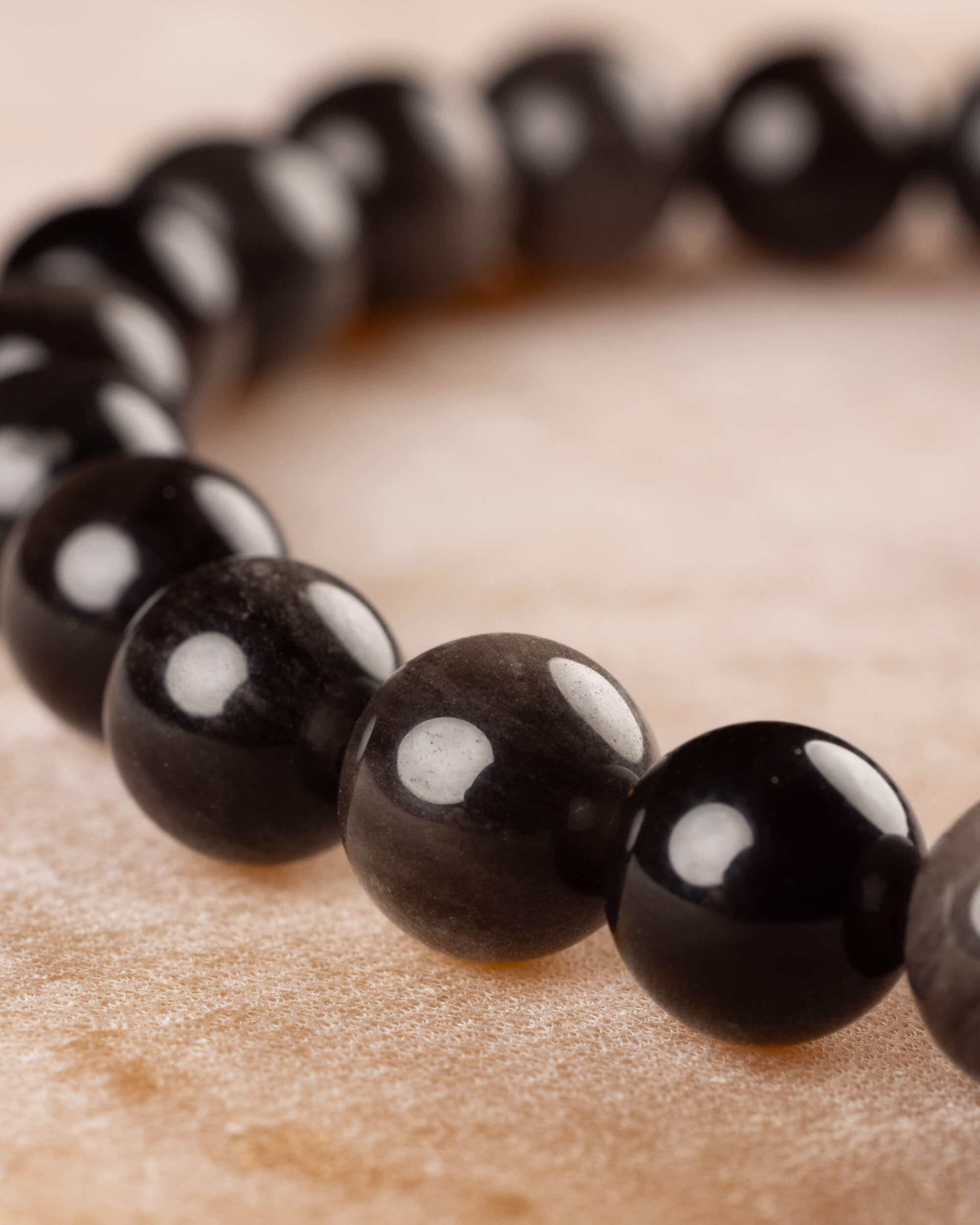 Pulsera de Obsidiana Plateada en ángulo bajo, mostrando el brillo de las cuentas negras y grises