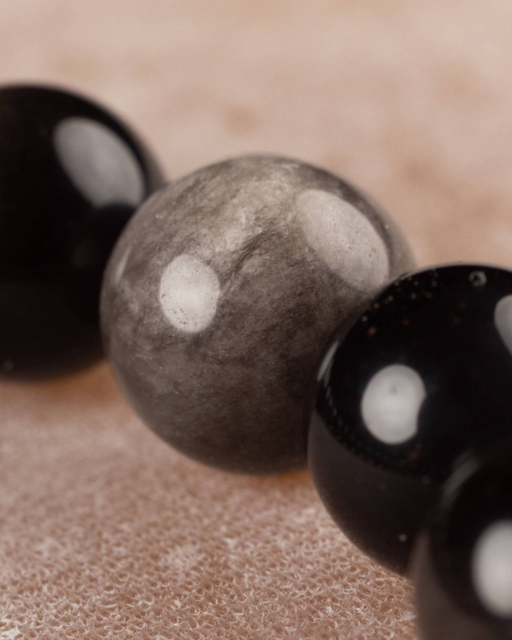Detalle macro de las cuentas de Obsidiana Plateada, con su reflejo gris característico