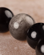 Detalle macro de las cuentas de Obsidiana Plateada, con su reflejo gris característico