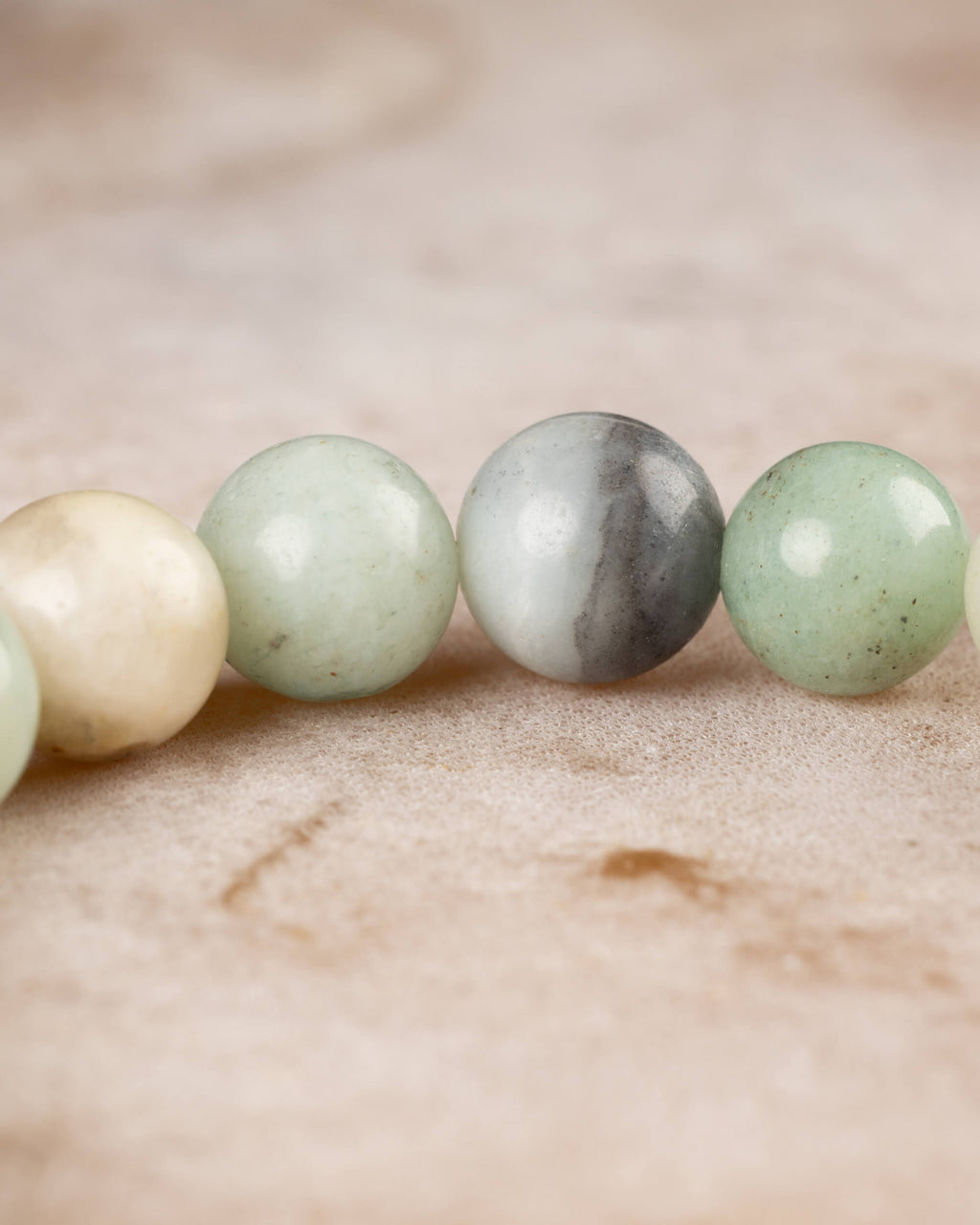 Detalle macro de cuentas de Amazonita en tonos crema, verde y gris
