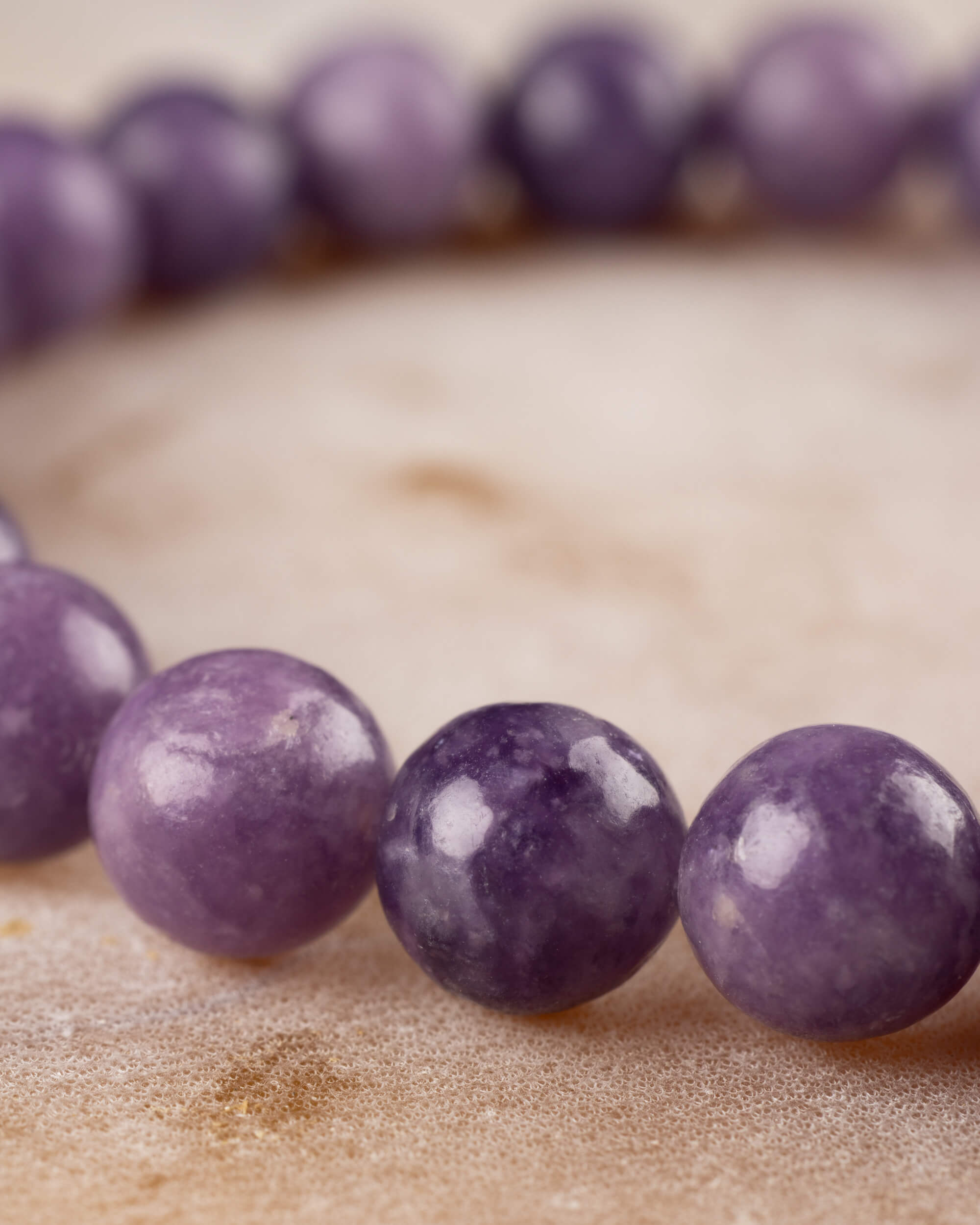 Pulsera de Lepidolita Uva vista de cerca en curva, tonos morados