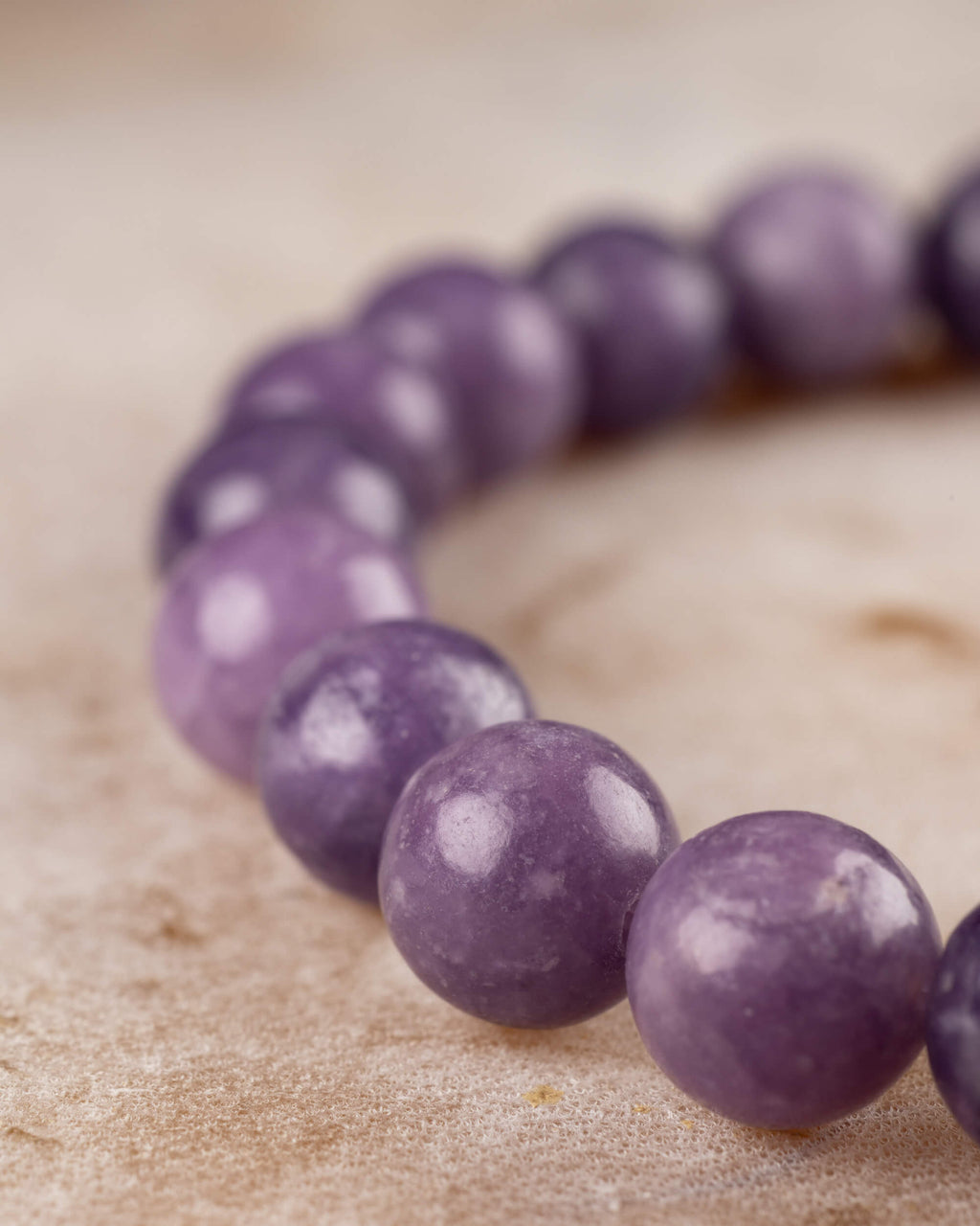 Pulsera de Lepidolita Uva en angulo curvo sobre superficie clara