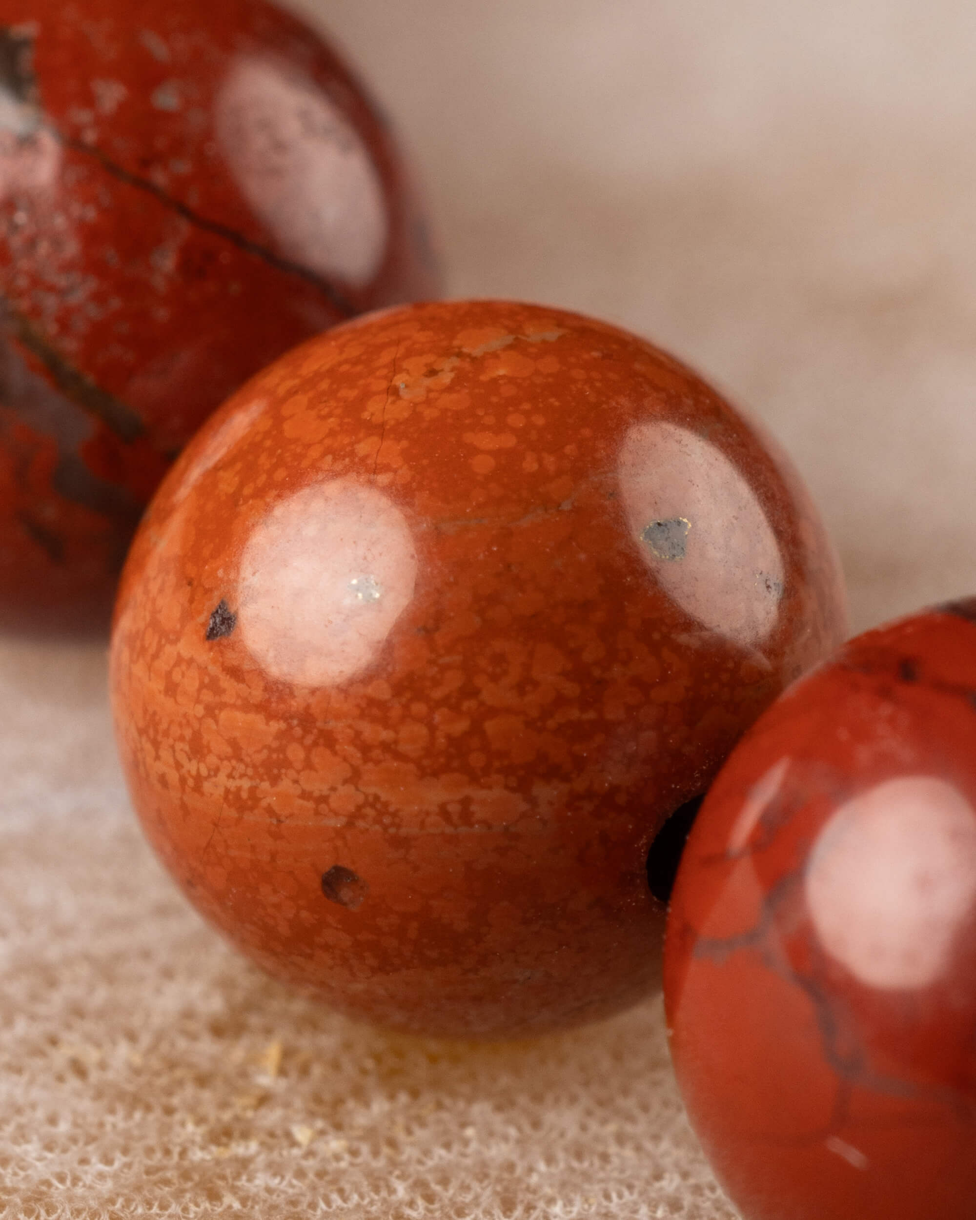 Detalle macro de una cuenta de Jaspe Rojo con vetas y motas claras