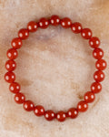 Pulsera de Cornalina de 8 mm, pieza completa en círculo sobre superficie de mármol claro