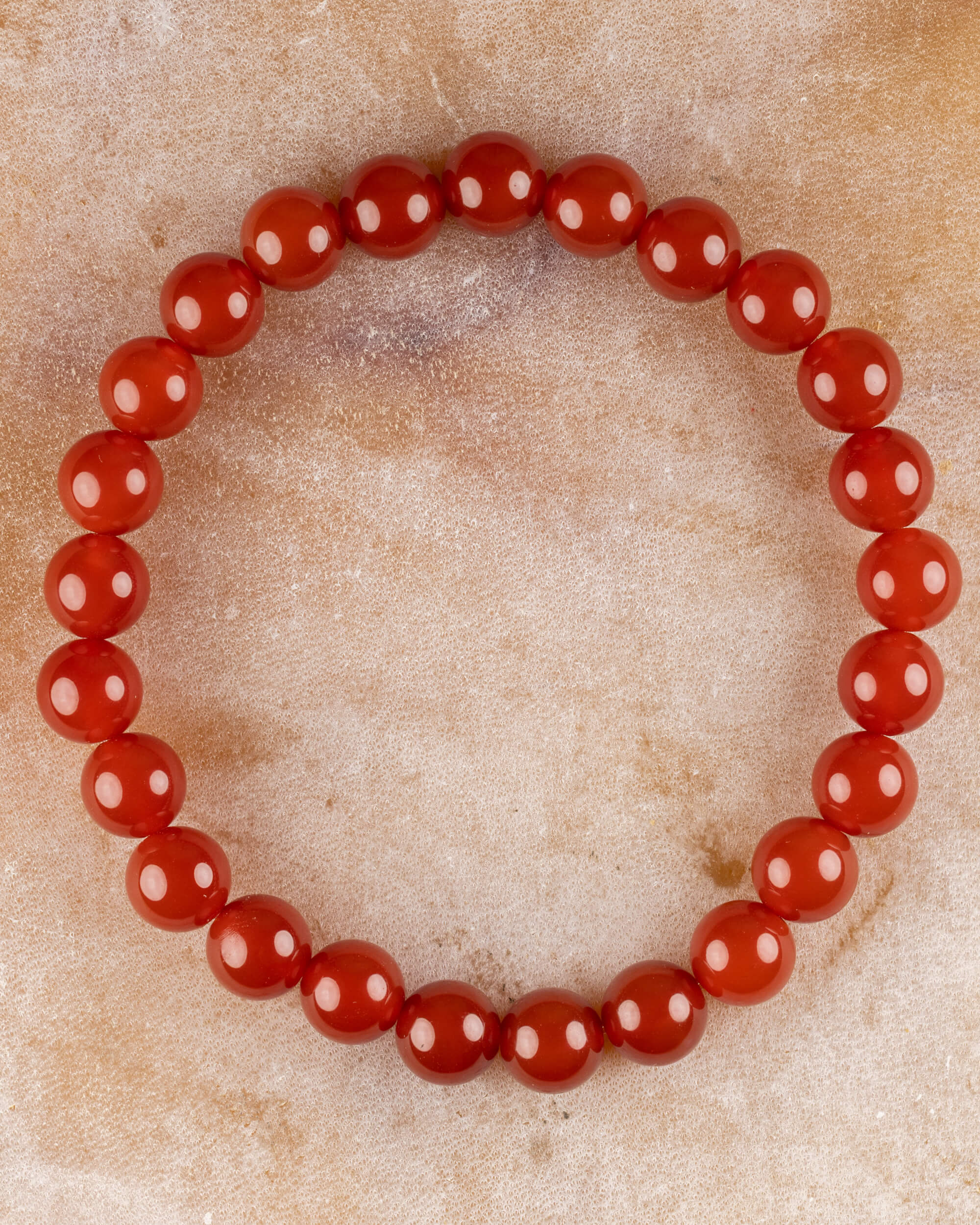 Pulsera de Cornalina de 8 mm, pieza completa en círculo sobre superficie de mármol claro