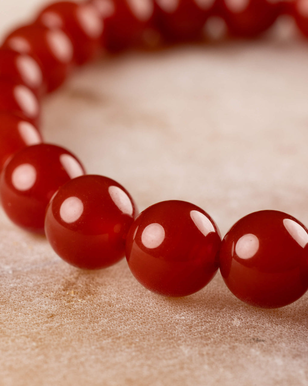 Pulsera de Cornalina desde ángulo cercano, cuentas en curva sobre tela clara