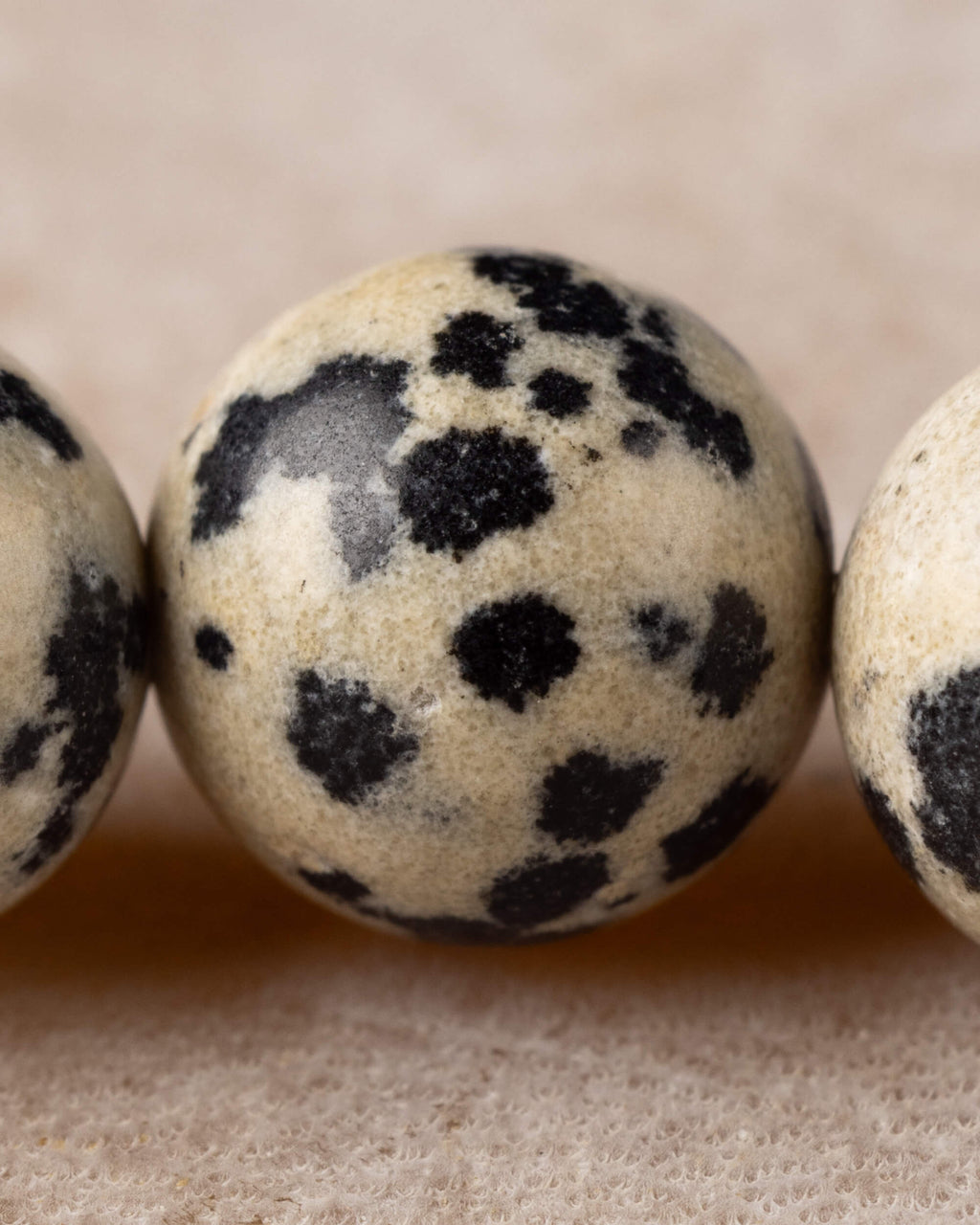Detalle macro de una cuenta de Jaspe Dalmata con manchas negras marcadas