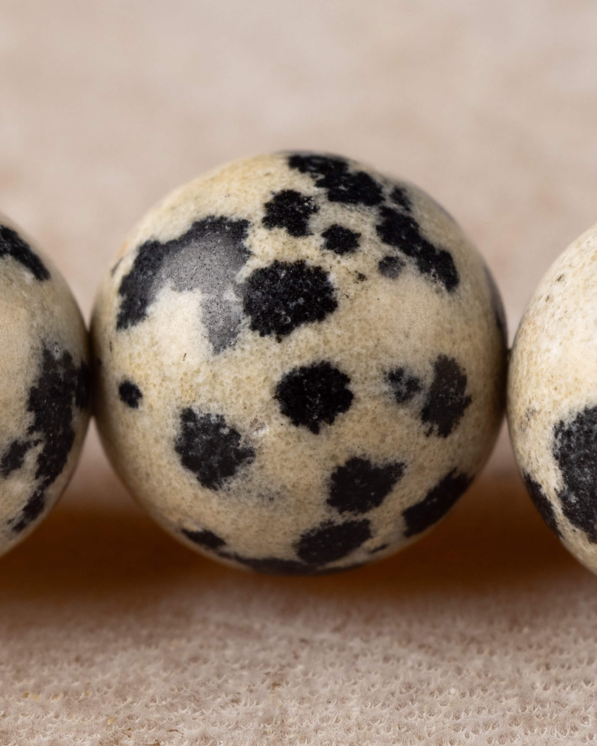 Detalle macro de una cuenta de Jaspe Dalmata con manchas negras marcadas