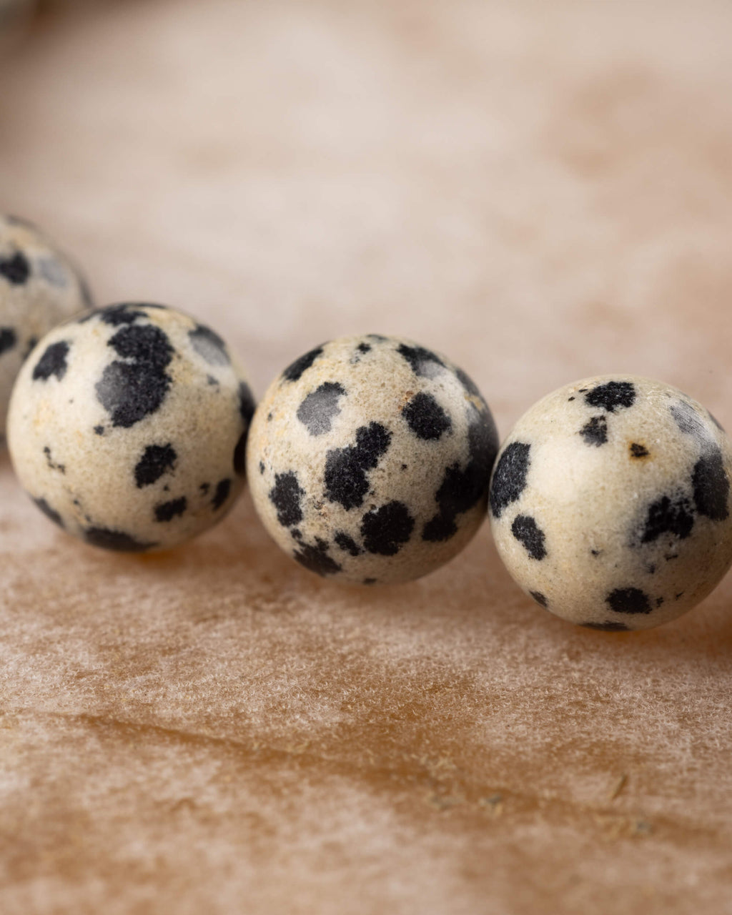 Cuentas de Jaspe Dalmata en secuencia, fondo crema con manchas oscuras