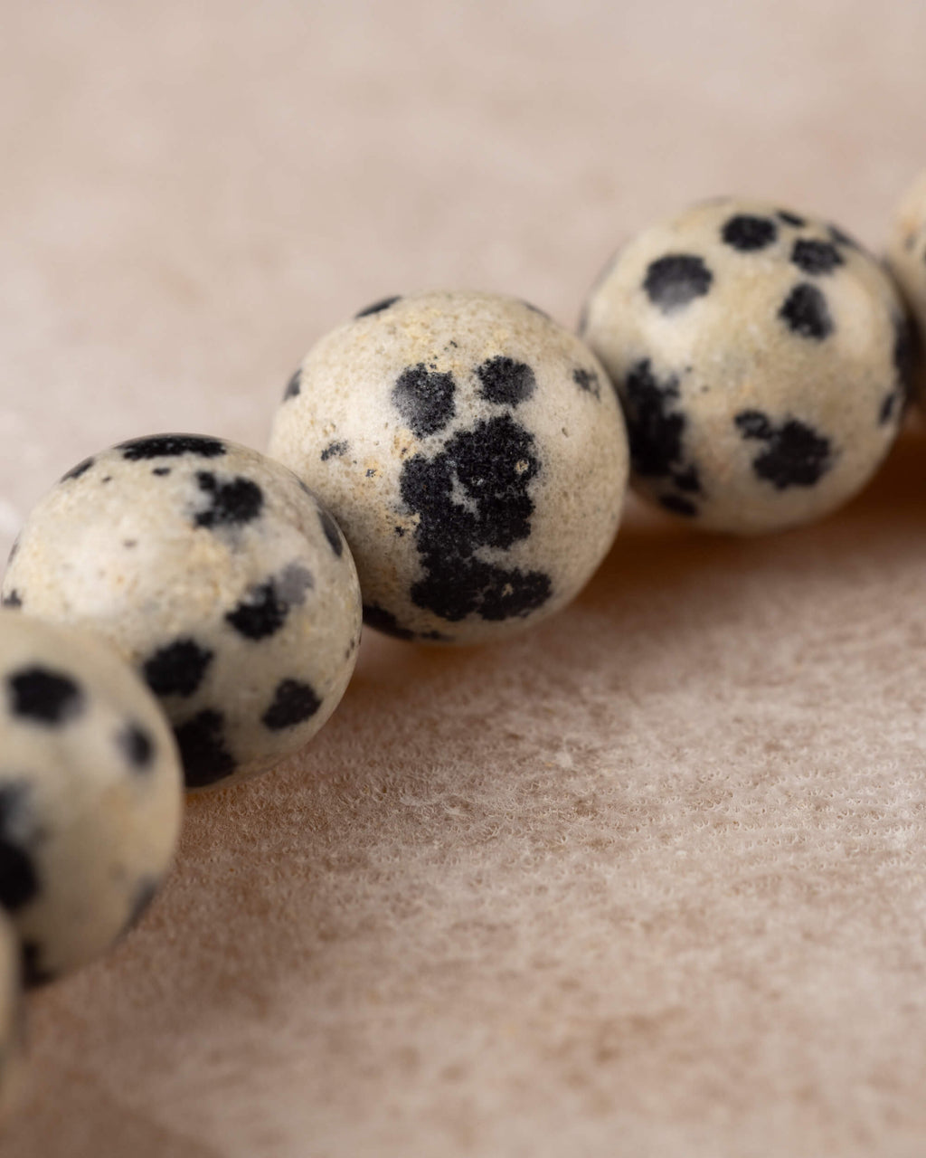 Detalle cercano de una cuenta de Jaspe Dalmata con manchas densas oscuras