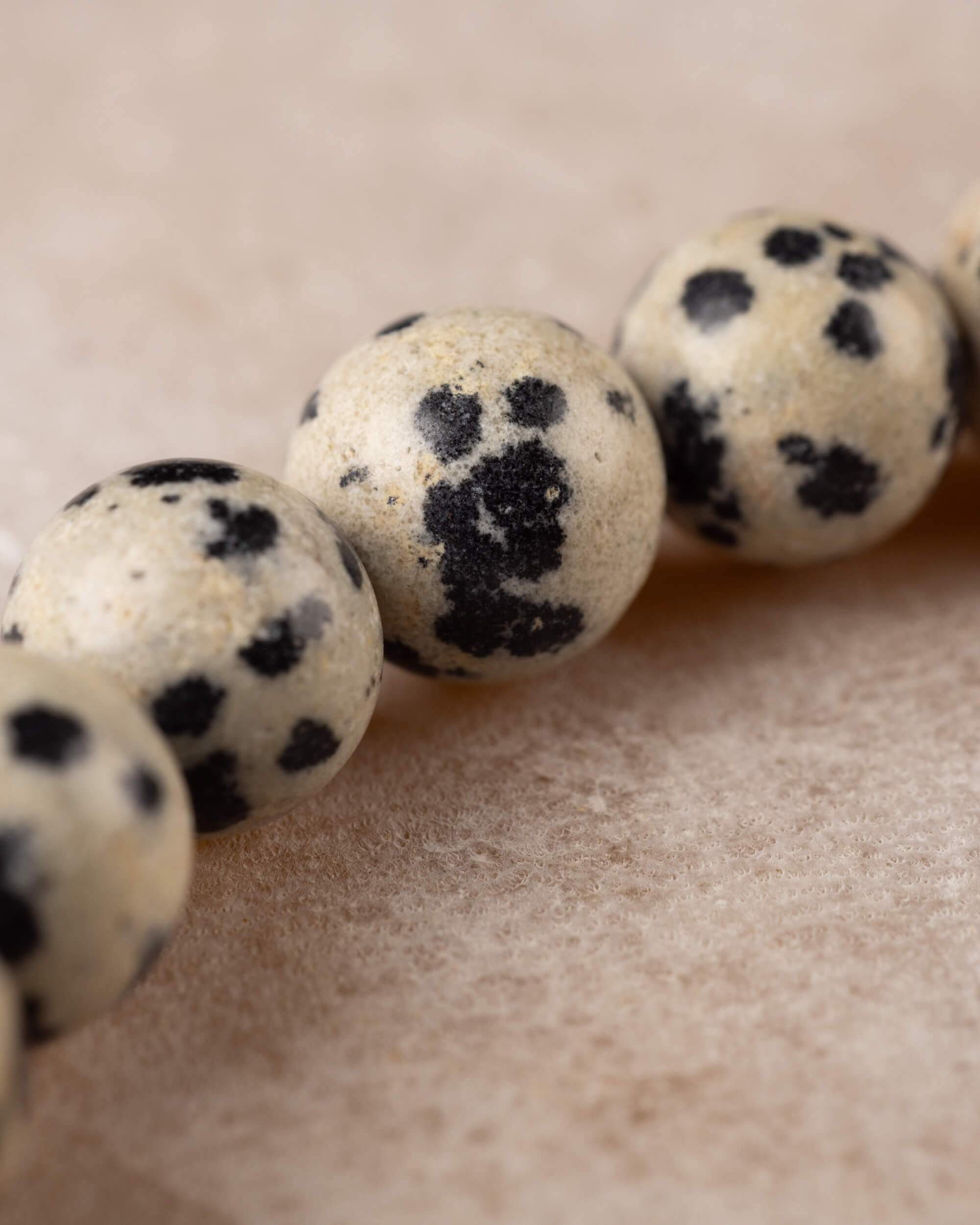 Detalle cercano de una cuenta de Jaspe Dalmata con manchas densas oscuras