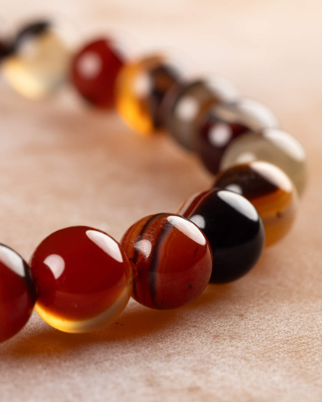 Pulsera de Cornalina Rojo y Negro mostrando la curva de cuentas con bandas